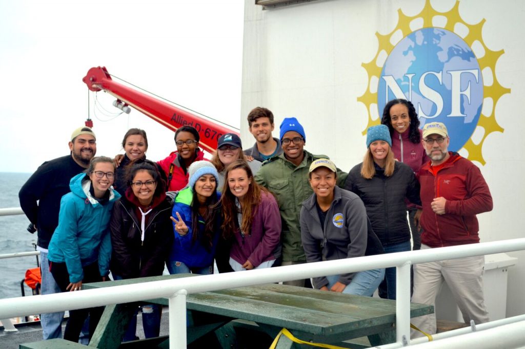group of smiling students aboard a ship with the NSF logo in the background